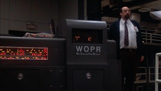 Irving Metzman as Richter standing next to the WOPR (War Operations Plan Response)